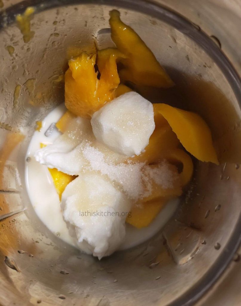 Blender jar with ingredients to make mango lassi.