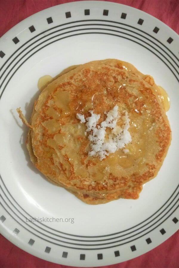 A plate with whole wheat coconut pancake with grated coconut on top.