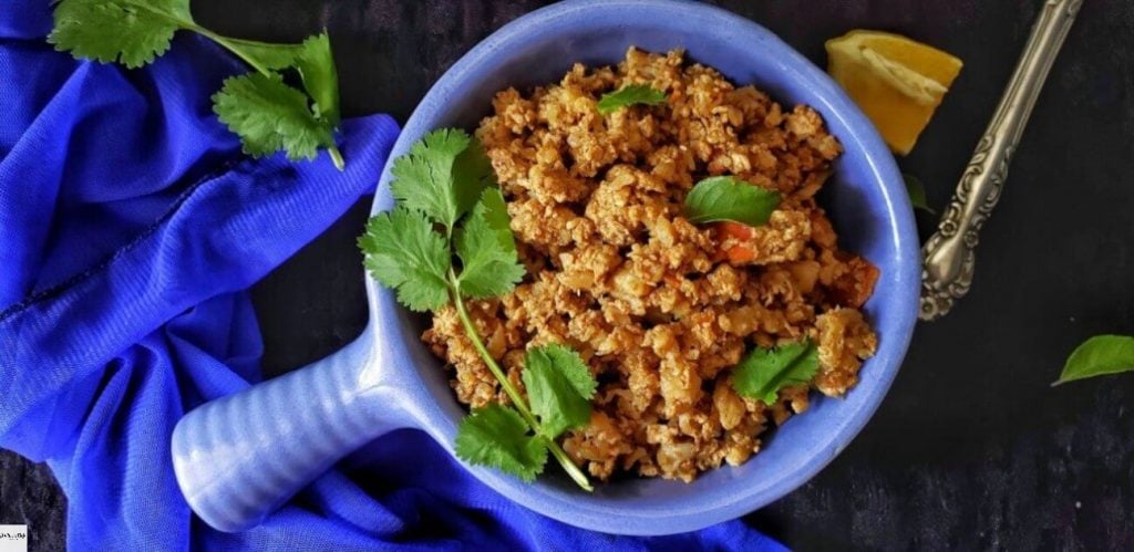 Bowl of Cauliflower Stir fry with lemon wedge on side.