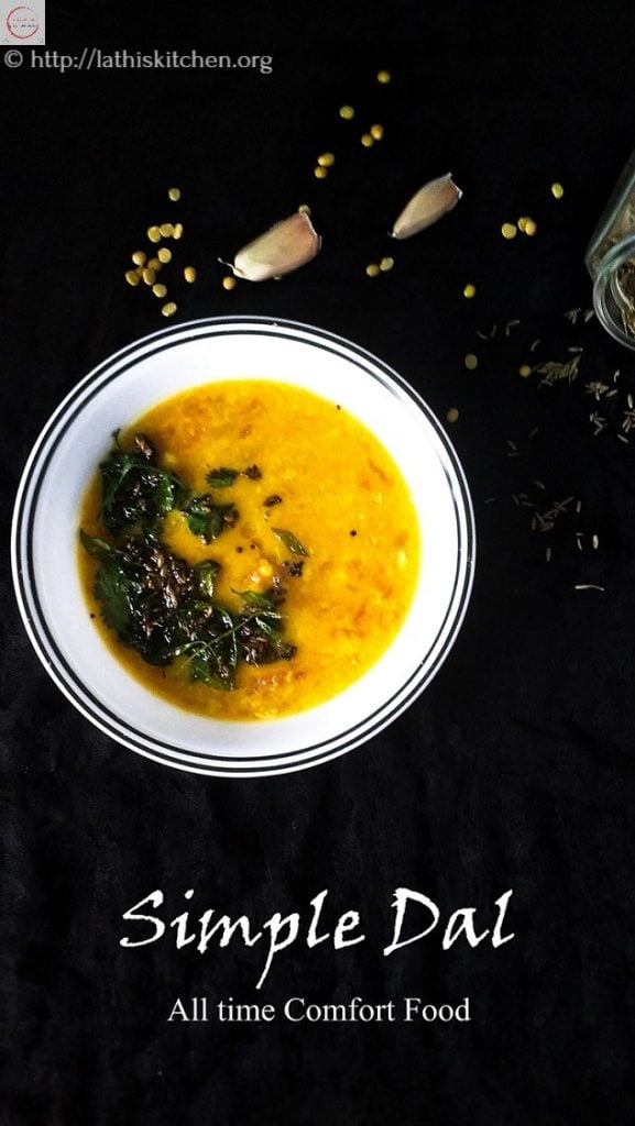 Bowl of simple dal with dal scattered on side along garlic pods.
