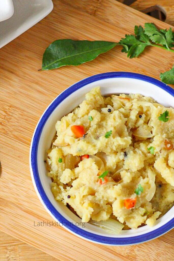 Bowl of Rava Upma with curry leaves on the side.