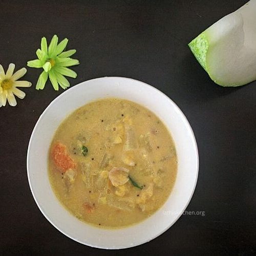 A bowl of kumbalanga paripu curry with ash gourd on the side and two flowers for decorative purpose.