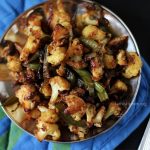 A plate of cauliflower capsicum stir fry with a spoon on side.