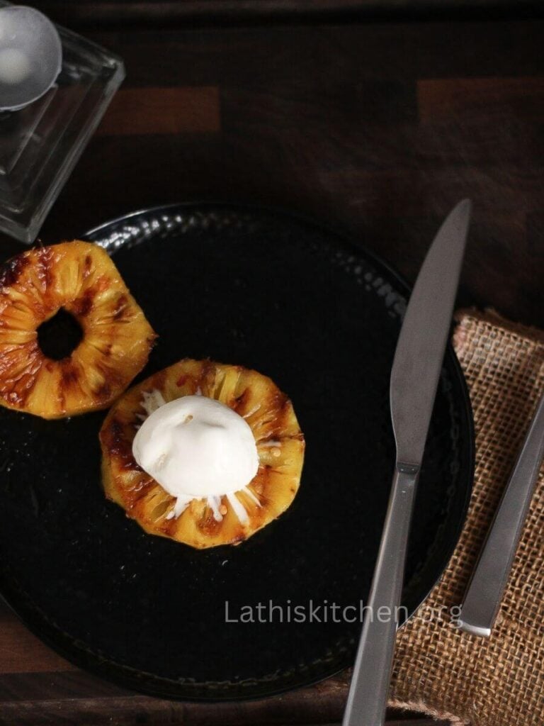 Two slices of grilled pineapple with a scoop of ice cream on one.