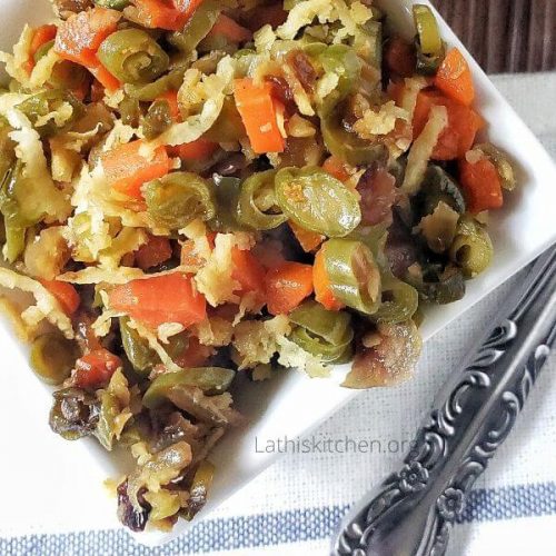 A boel of Carrot beans poriyal with a spoon on side.