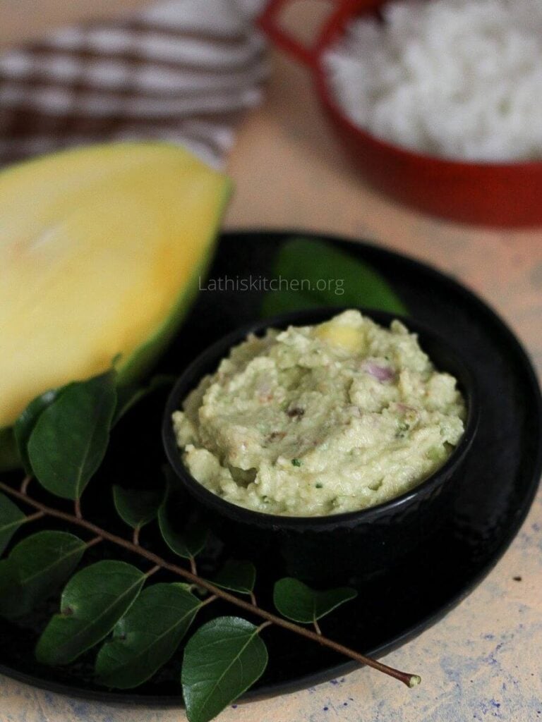 A bowl of raw mango chutney with a half cut raw mango on the side.