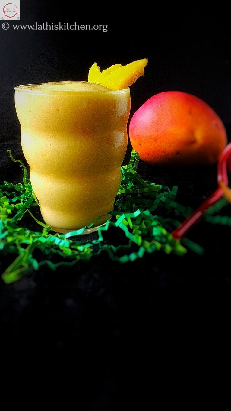Mango lime lassi in a glass with few mango slices.