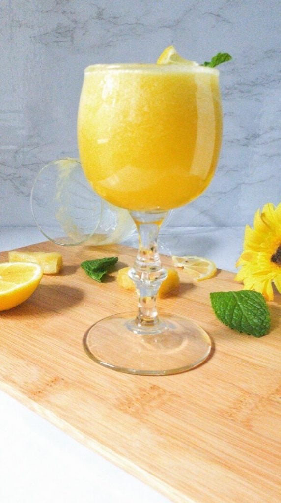 Glass of Pineapple Lemonade with slice of lemon and mint leaves.