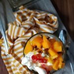 Glass of Mango Milkshake with Ice cream, nuts and mango chunks.