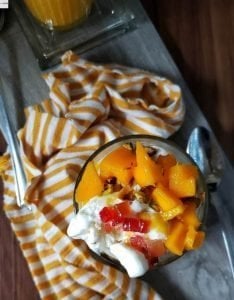 Glass of Mango Milkshake with Ice cream, nuts and mango chunks.