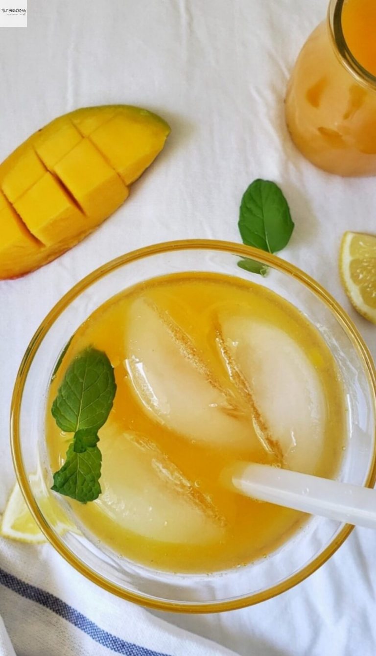 Glass of Mango Lemonade with Mango and lemon wedges on side.