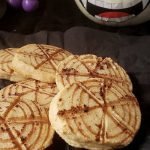 Halloween spider web cookies with pumpkin in the background.