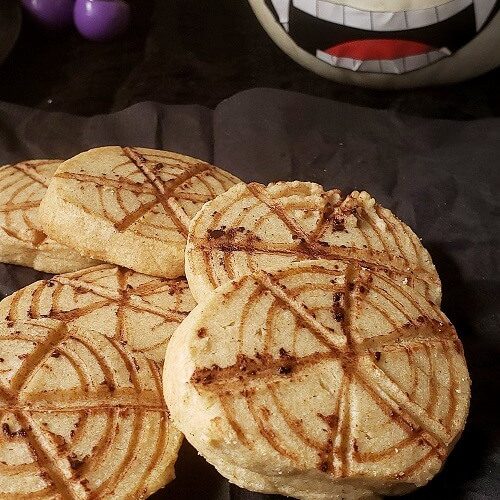 Halloween spider web cookies with pumpkin in the background.