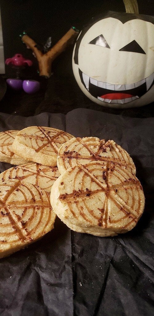 Halloween spider web cookies with pumpkin in the background.