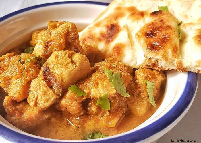 Bowl of Instant pot Chicken Tikka Masala with a piece of Naan.