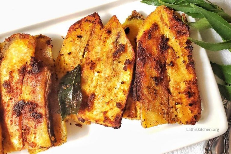 A plate of raw banana fry with sprig of curry leaves on side.