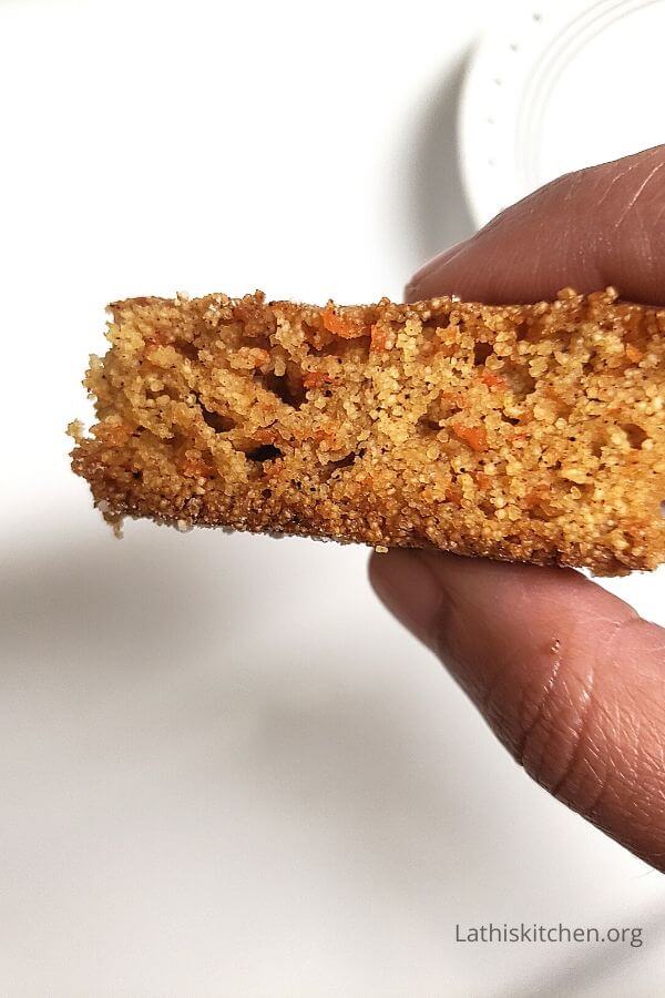 Hand holding a piece of carrot cake.