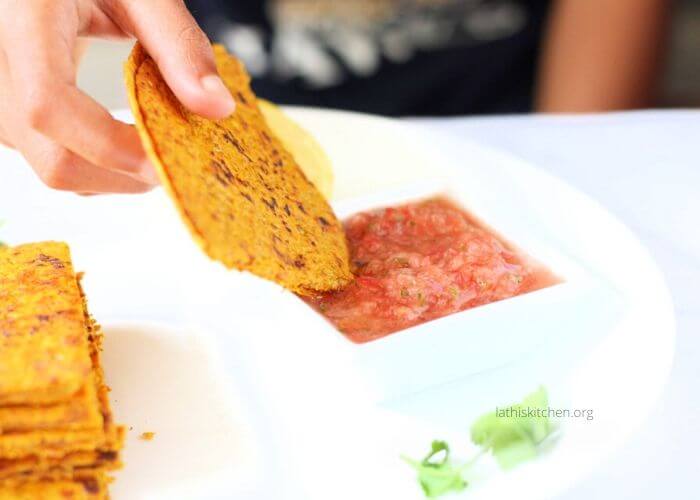 A hand dipping cheese quesadilla in salsa.