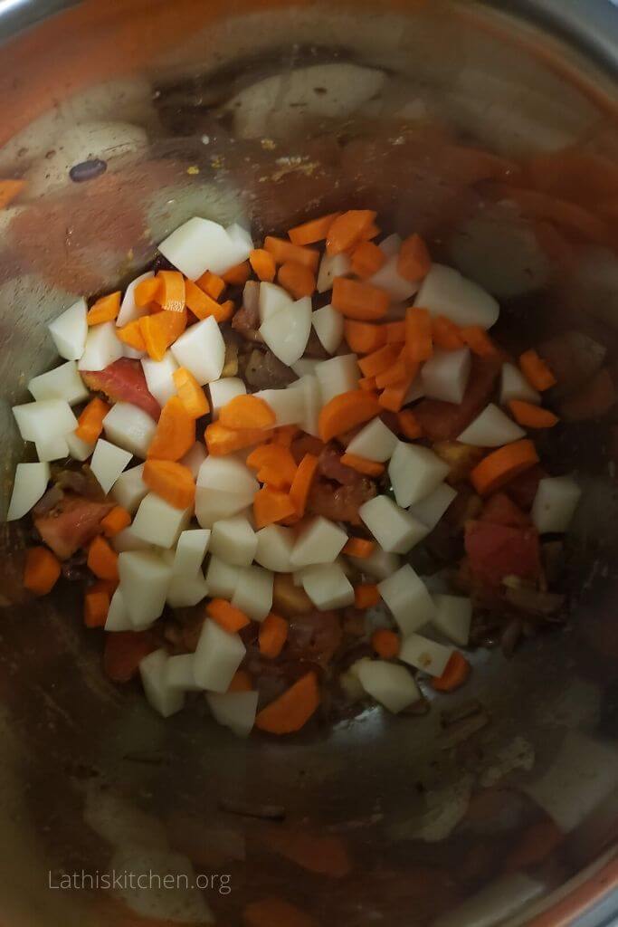 Cubed potatoes and carrot in Instant pot with Onion and tomato masala.