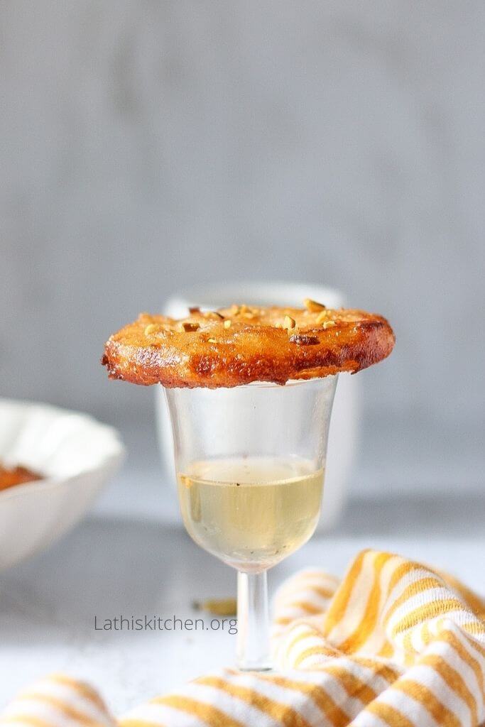 Apple Jalebi on top of a glass with sugar syrup.