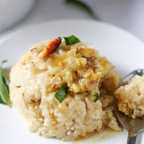 A spoon scooped Ven pongal in a plate.