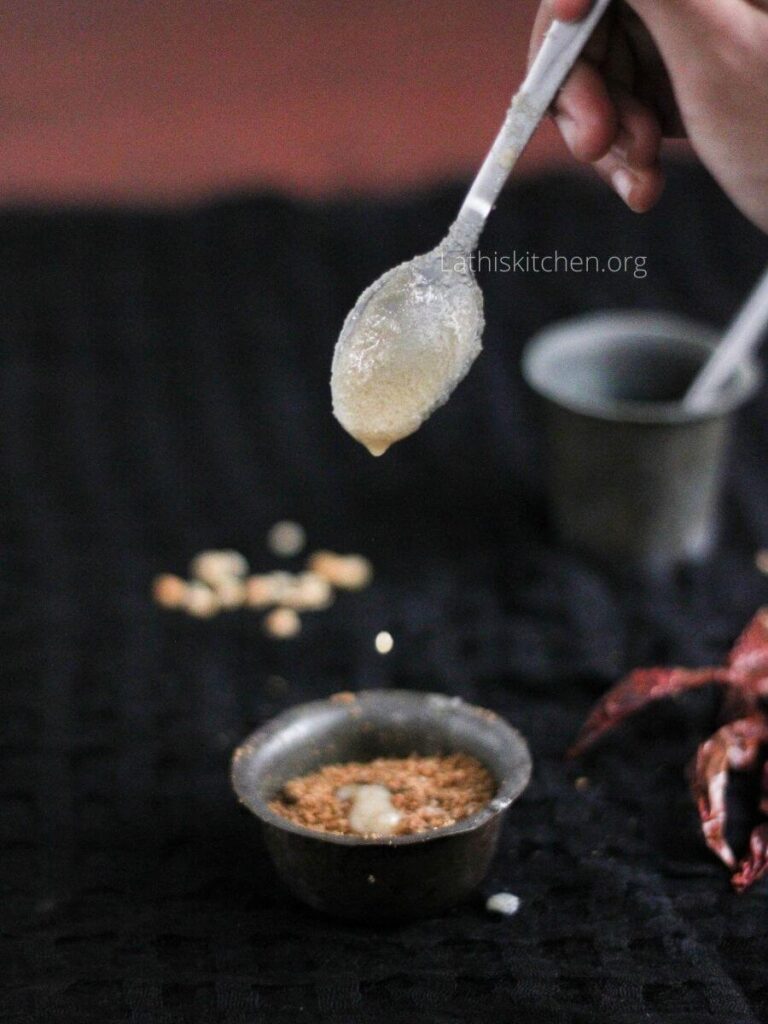 Ghee dripping from a spoon over the bowl with Ellu podi.