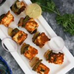 Head shot view of paneer tikka on the plate with lemon slice.