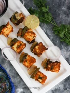 Head shot view of paneer tikka on the plate with lemon slice.