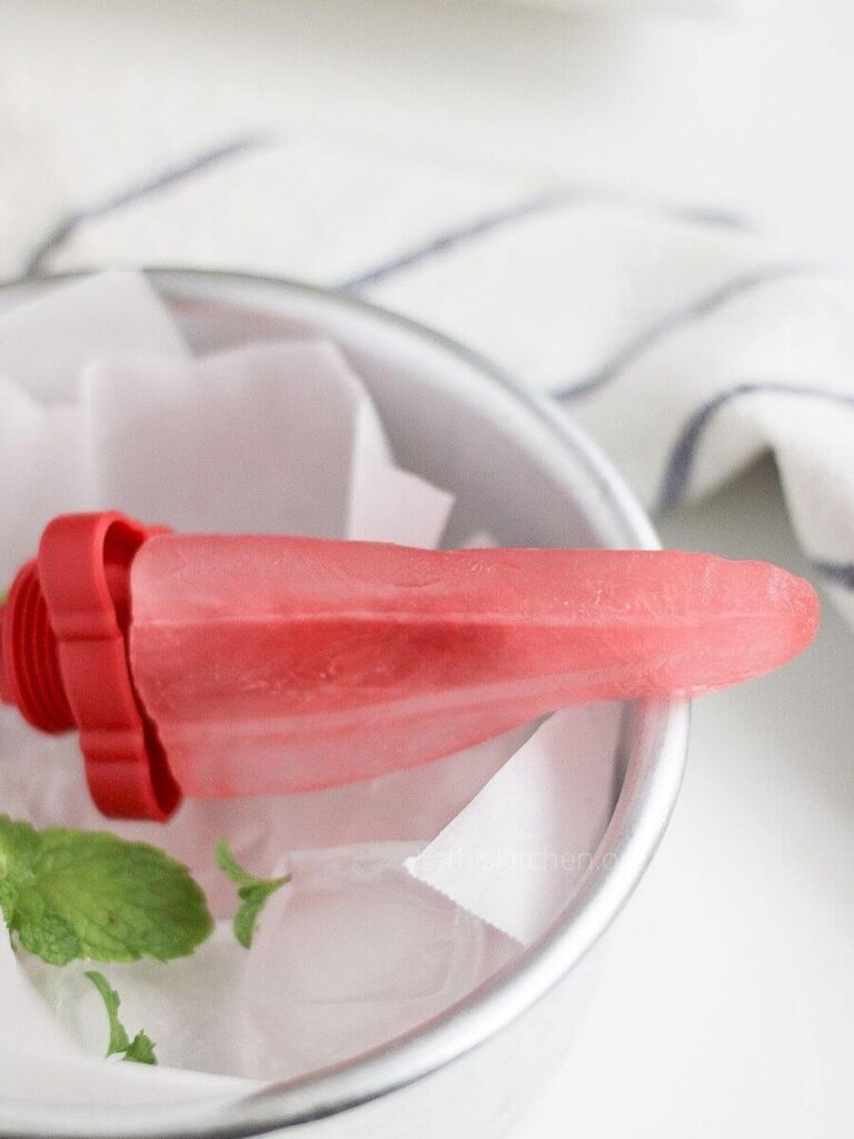 A hibiscus lemon popsicle in a bowl with parchment paper.