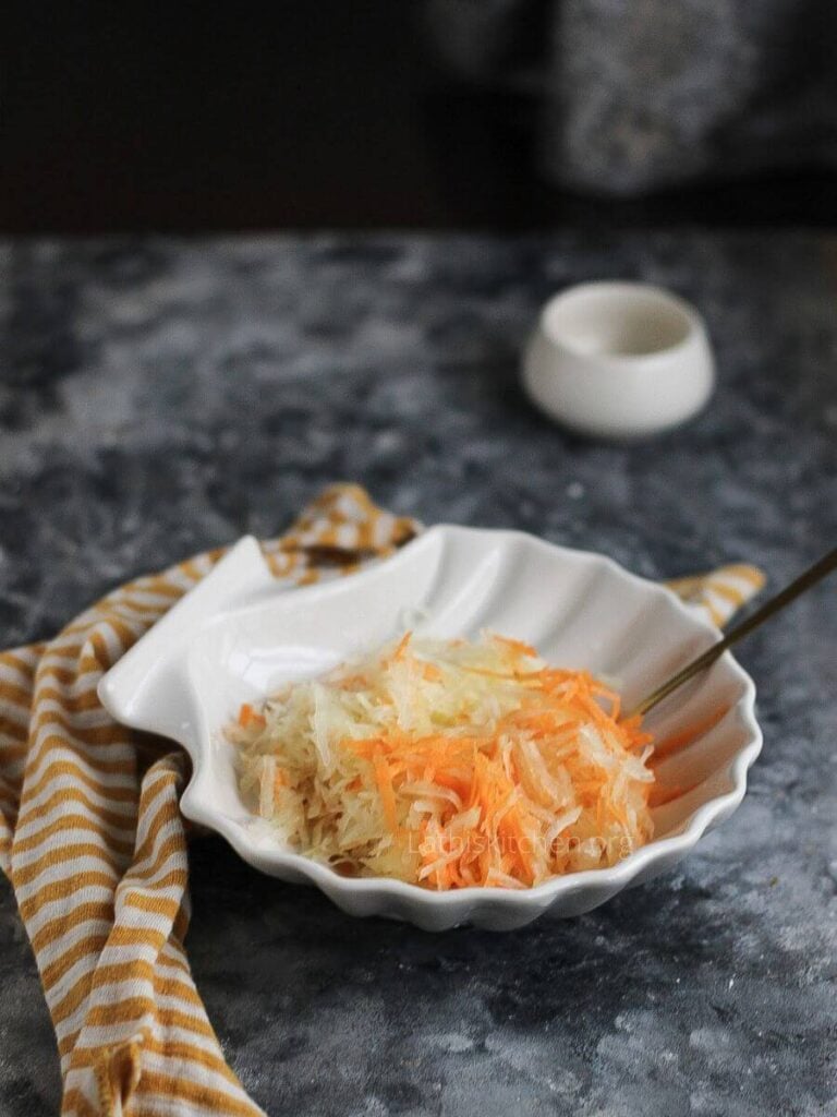 Grated raw papaya and carrot in a bowl.