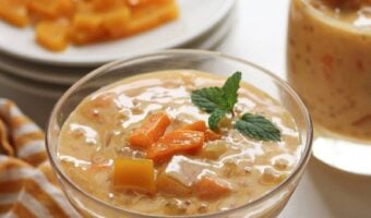 A cup with mango sago with condensed milk and a mint leaf on top.